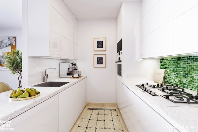 kitchen with white gas stovetop, sink, white cabinets, and decorative backsplash