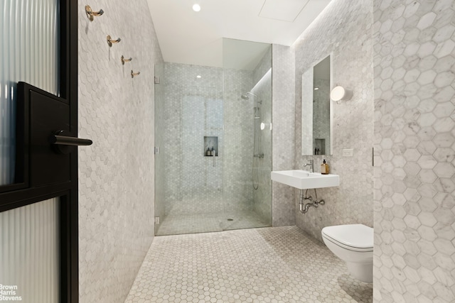 full bathroom with a sink, a shower stall, tile walls, toilet, and tile patterned floors