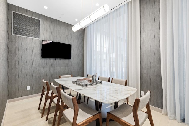 dining room featuring wallpapered walls, baseboards, and light wood-type flooring