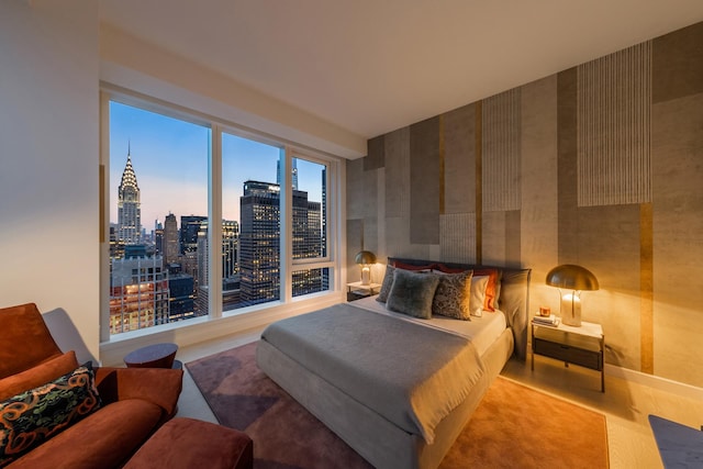 bedroom featuring a view of city, wood finished floors, and wallpapered walls