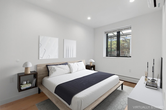bedroom with light wood-style flooring, recessed lighting, a baseboard heating unit, and baseboards