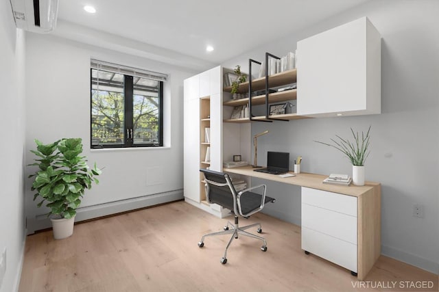 office area with an AC wall unit, built in desk, baseboard heating, and light hardwood / wood-style floors