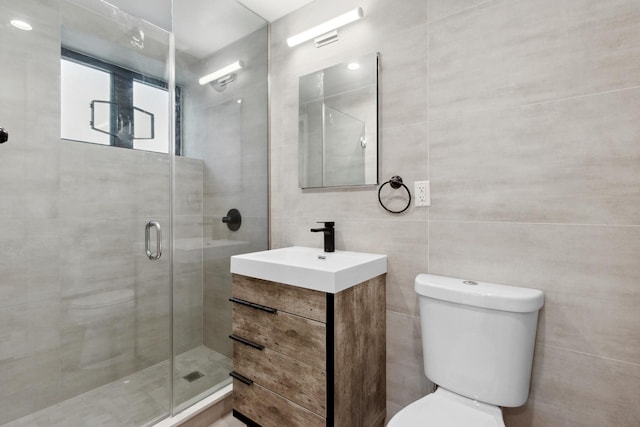 full bathroom featuring toilet, tile walls, a stall shower, and vanity