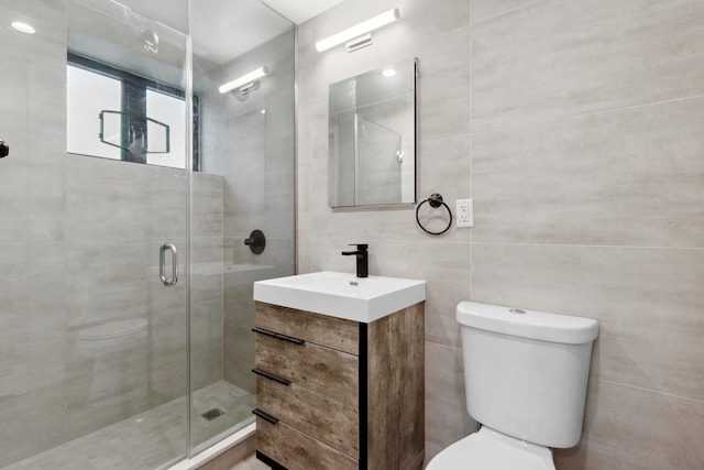 full bath with toilet, a shower stall, tile walls, and vanity