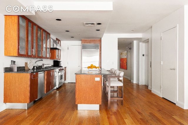 kitchen featuring high quality appliances, a breakfast bar, a center island, sink, and dark hardwood / wood-style floors