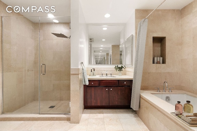 bathroom with tile patterned floors, separate shower and tub, tile walls, and vanity