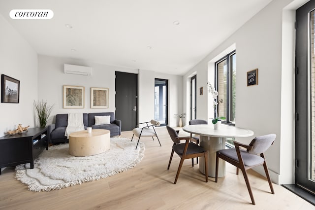 dining room featuring an AC wall unit and light hardwood / wood-style floors