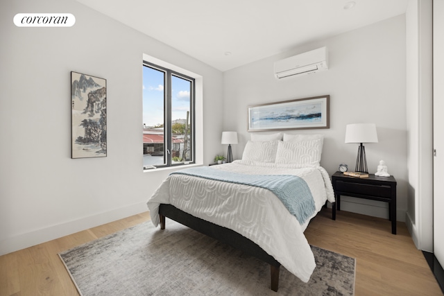 bedroom featuring hardwood / wood-style flooring and an AC wall unit