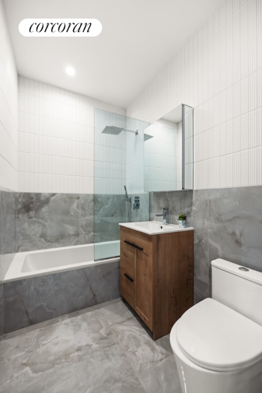 full bathroom with vanity, tile walls, toilet, and tiled shower / bath