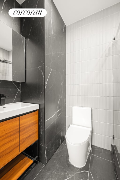 bathroom with tile walls, toilet, and vanity