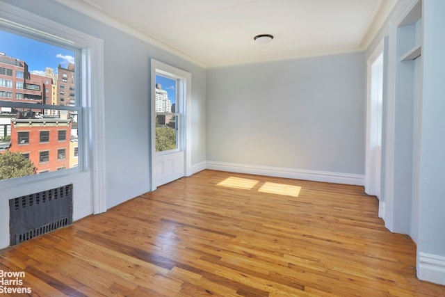 spare room featuring radiator, crown molding, and light hardwood / wood-style flooring