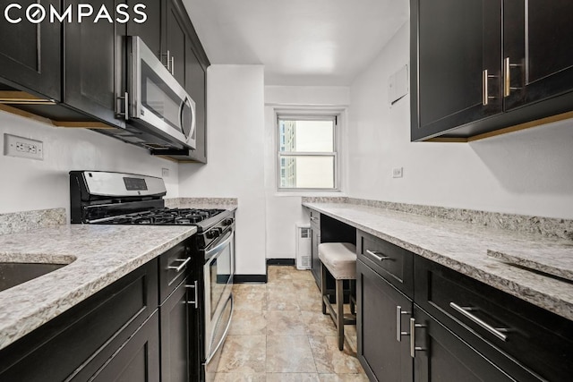 kitchen featuring light stone counters, radiator heating unit, and stainless steel appliances