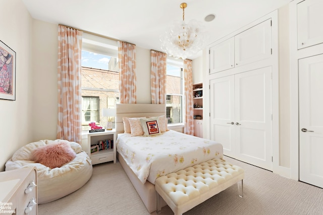 bedroom with a closet, a notable chandelier, and light carpet