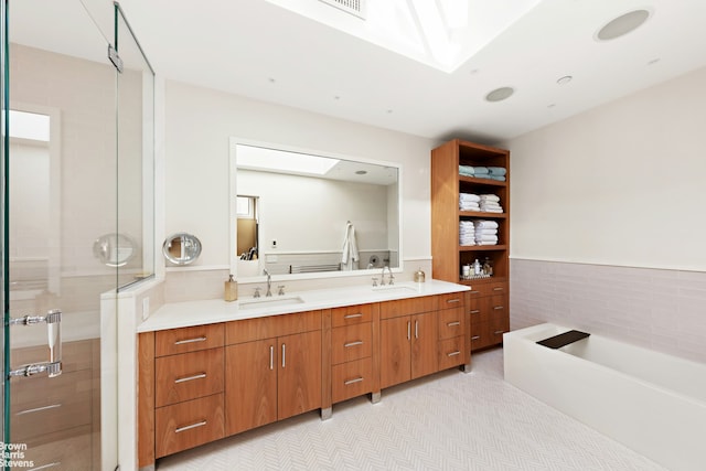 full bath with double vanity, a skylight, and a sink