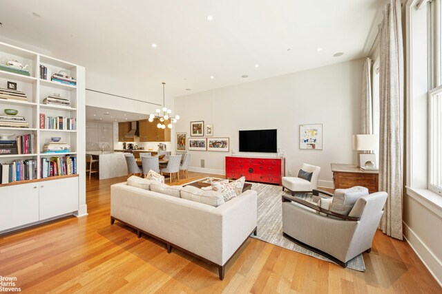 living area with recessed lighting, light wood-style floors, baseboards, and a chandelier