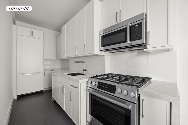 kitchen with a sink, decorative backsplash, dark tile patterned flooring, and appliances with stainless steel finishes