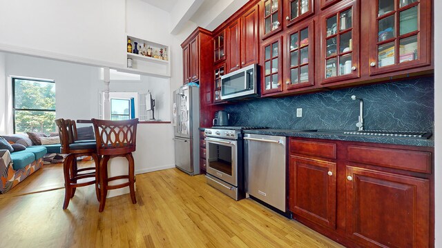 kitchen featuring tasteful backsplash, appliances with stainless steel finishes, sink, and light wood-type flooring