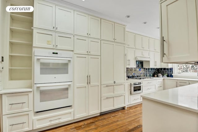 kitchen with stainless steel gas cooktop, double oven, backsplash, and hardwood / wood-style floors