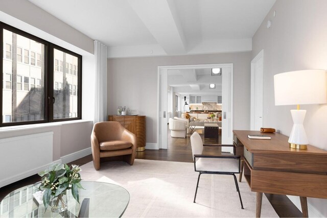 sitting room with beamed ceiling, wood-type flooring, and a wealth of natural light