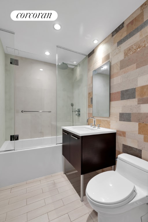 full bathroom featuring shower / washtub combination, toilet, tile walls, and vanity