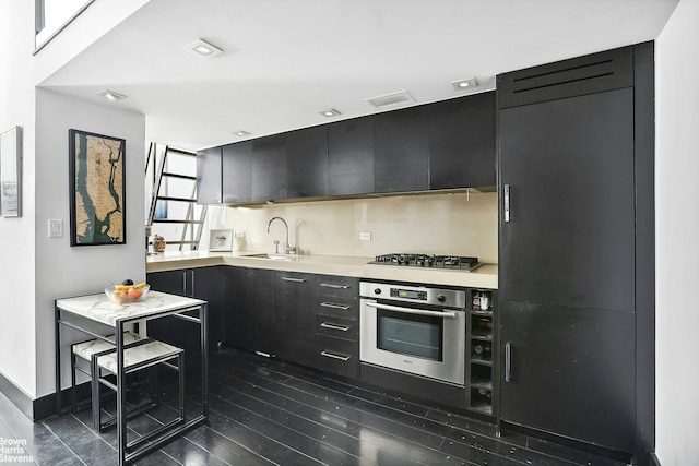 kitchen featuring light countertops, appliances with stainless steel finishes, a sink, and dark cabinetry