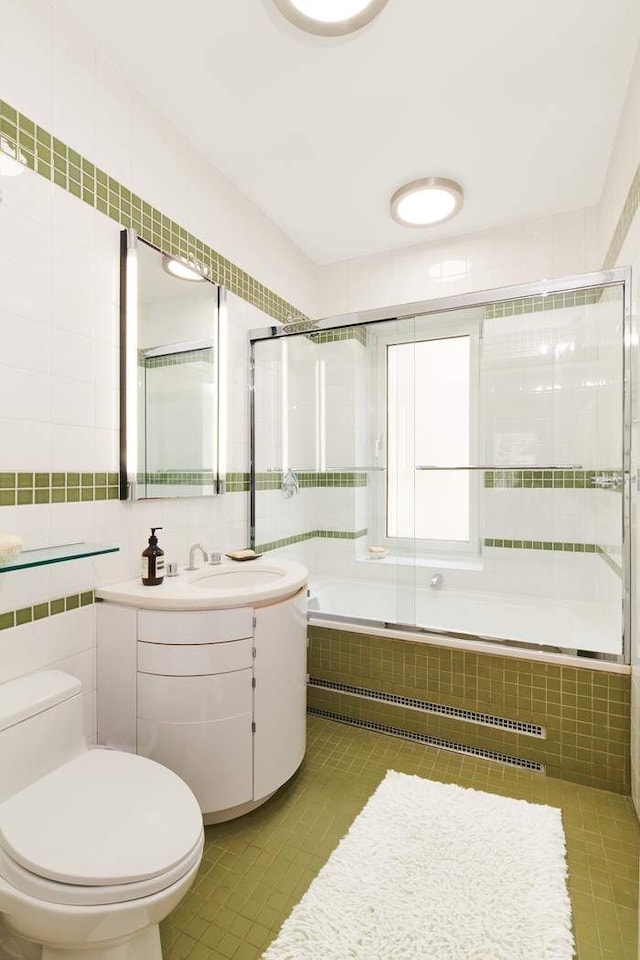 full bathroom featuring tile patterned flooring, toilet, vanity, tile walls, and tiled shower / bath