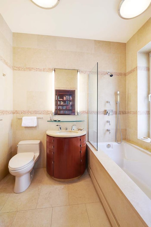 bathroom with toilet, tile patterned floors, tiled shower / bath, vanity, and tile walls