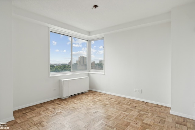 unfurnished room featuring radiator and baseboards