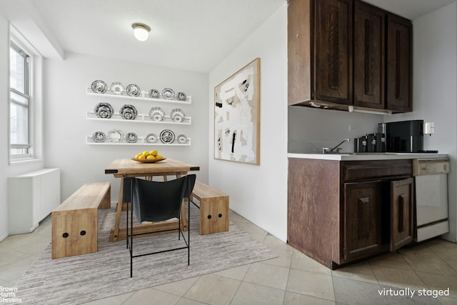 kitchen featuring dishwasher, light countertops, a sink, and dark brown cabinetry