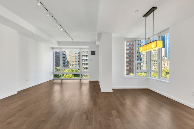 unfurnished living room with dark hardwood / wood-style floors and track lighting