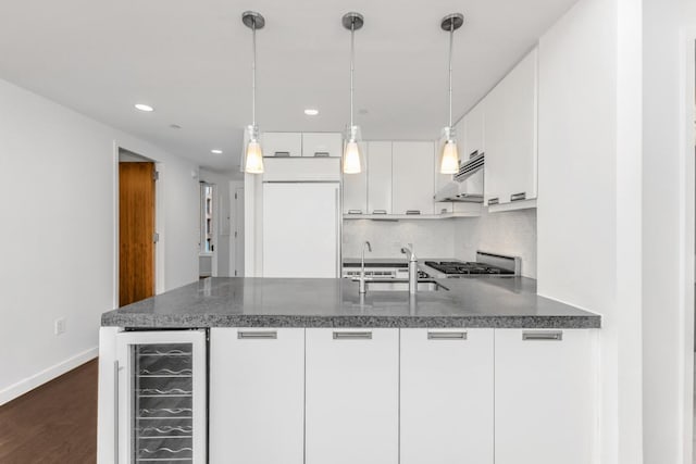 kitchen with white cabinets, wine cooler, decorative backsplash, sink, and hanging light fixtures