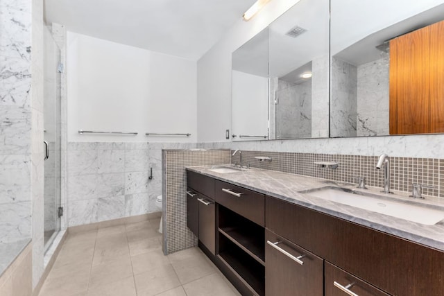 bathroom with tile walls, toilet, a shower with door, and tile patterned flooring