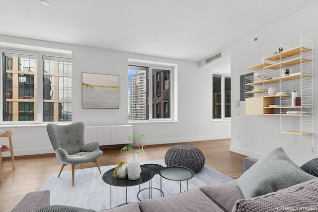 living area with baseboards, visible vents, and wood finished floors