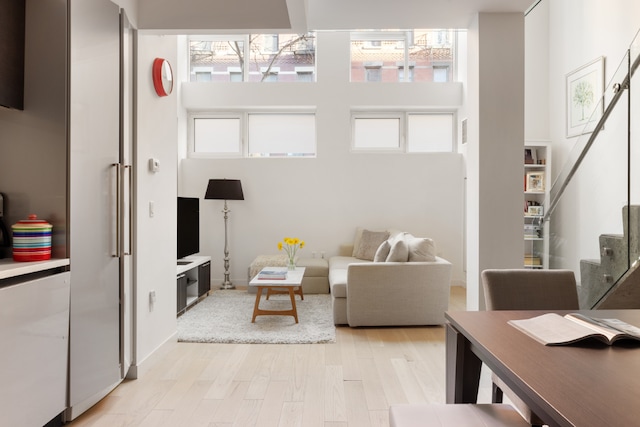 living room with a towering ceiling, plenty of natural light, and light hardwood / wood-style flooring