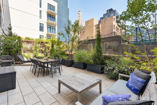 view of patio / terrace featuring outdoor dining area, a city view, and fence