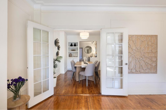 dining room with french doors, built in features, ornamental molding, and wood-type flooring