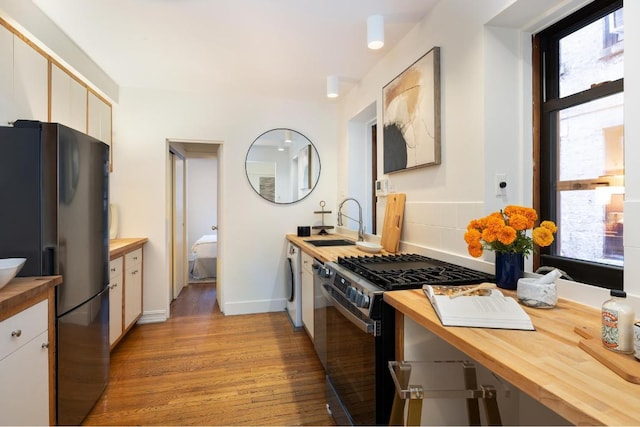 kitchen featuring sink, butcher block countertops, appliances with stainless steel finishes, and light wood-type flooring