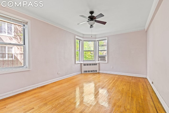 unfurnished room with light hardwood / wood-style floors, radiator heating unit, ornamental molding, and ceiling fan