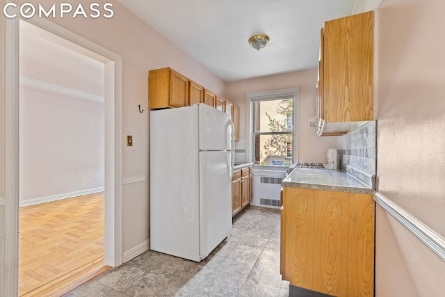 kitchen featuring decorative backsplash, radiator heating unit, and white fridge