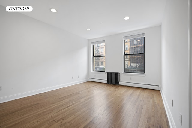 spare room featuring a baseboard radiator, wood finished floors, recessed lighting, and baseboards