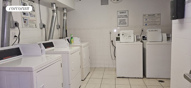 clothes washing area featuring separate washer and dryer, tile walls, and light tile patterned floors