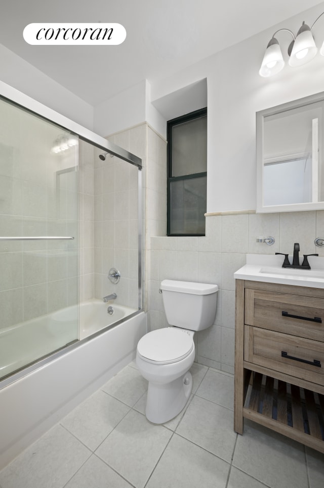 bathroom featuring tile walls, tile patterned flooring, toilet, vanity, and enclosed tub / shower combo