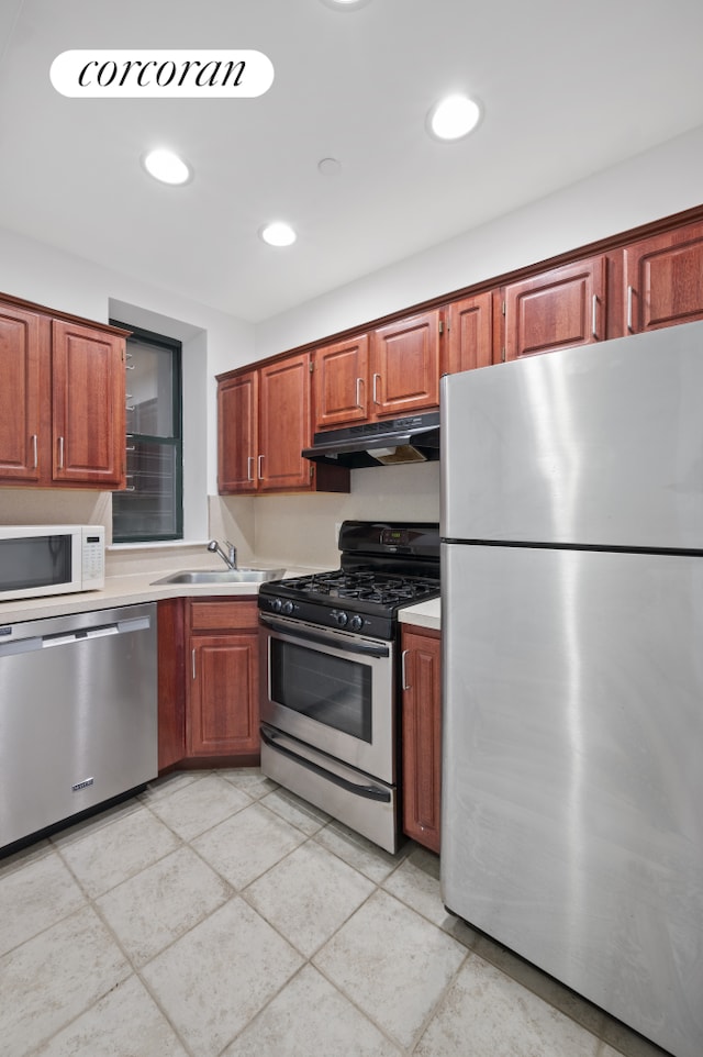 kitchen with stainless steel appliances, under cabinet range hood, light countertops, a sink, and recessed lighting