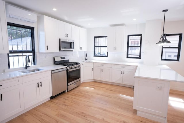 kitchen featuring white cabinetry, hanging light fixtures, kitchen peninsula, and appliances with stainless steel finishes