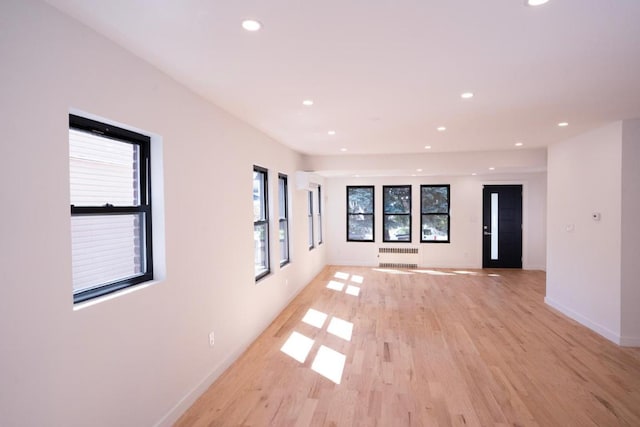 unfurnished room with radiator heating unit and light wood-type flooring