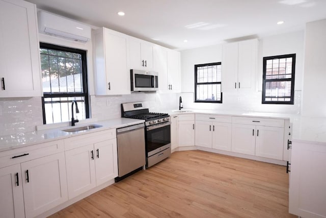 kitchen featuring appliances with stainless steel finishes, sink, a wall mounted air conditioner, and white cabinets