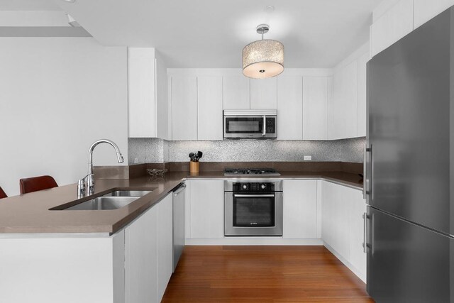 kitchen featuring sink, white cabinetry, appliances with stainless steel finishes, and kitchen peninsula