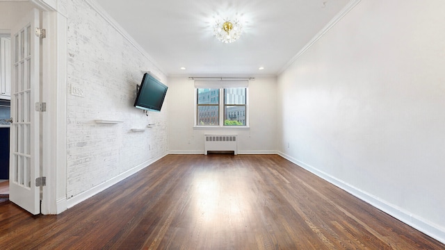 unfurnished living room featuring ornamental molding, radiator heating unit, dark hardwood / wood-style floors, and brick wall