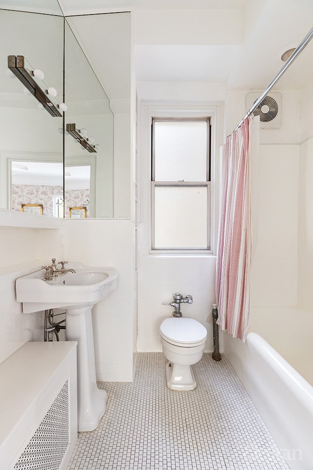 bathroom featuring tile patterned flooring, tile walls, toilet, and shower / bath combo with shower curtain