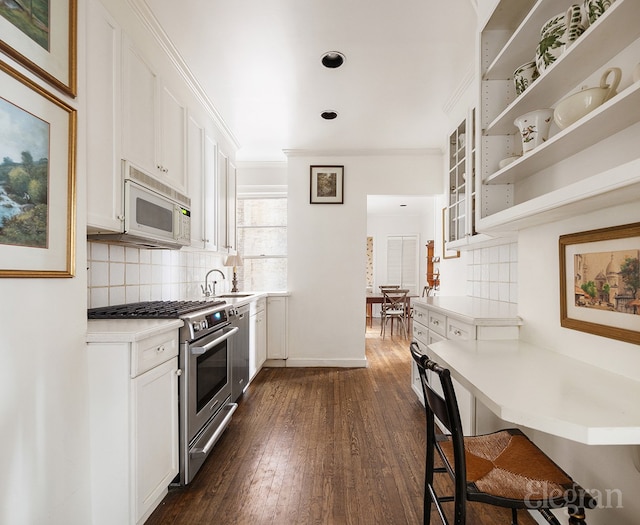 kitchen featuring stainless steel appliances, dark wood-style flooring, a sink, and white cabinetry